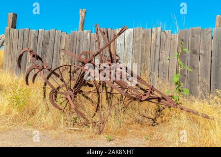 Alte vintage landwirtschaftlichen Traktor gegen Gräser und holzzaun an einem sonnigen Tag Stockfoto