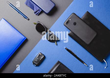 Einstellen der Männer Accessoires, Sonnenbrillen, Agenda, Autoschlüssel, Stift, über zwei Farben kreativ Hintergrund smartphone. Flache Schicht, minimalistisches Konzept. Stockfoto