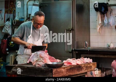 HongKong, China - November, 2019: Metzger schneidet Fleisch Metzgerei in Hongkong Stockfoto