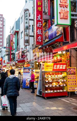Chinatown Nankin-Machi in Motomachi, Kobe, Japan. Abendlicher Blick entlang der Reihe von chinesischen Imbissbuden und Restaurants mit außerhalb tout als Menschen zu Fuss. Stockfoto