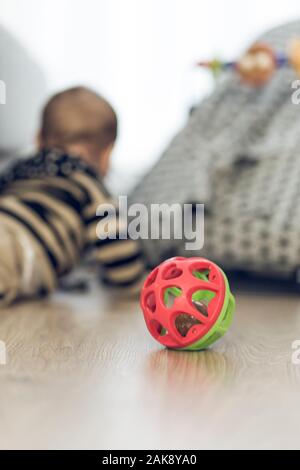 Rot und Grün baby Spielzeug auf einem Holzboden mit blurry Baby auf dem Hintergrund Stockfoto