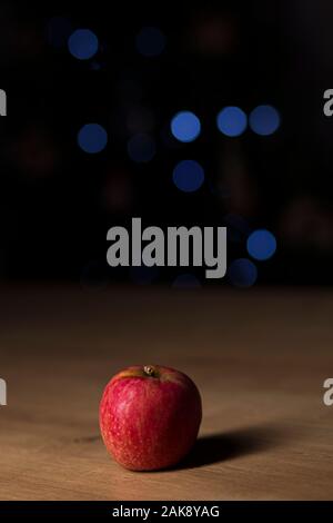 Roter Apfel auf einem Holztisch auf einem dunklen verschwommenen Hintergrund isoliert Stockfoto