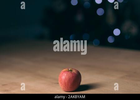 Roter Apfel auf einem Holztisch auf einem dunklen verschwommenen Hintergrund isoliert Stockfoto