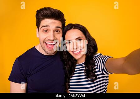 Self Portrait von charmanten Schöne nette Paar Ehegatten lächelnd in die Kamera, ihre Zähne zeigen, während mit gelbem Hintergrund Stockfoto