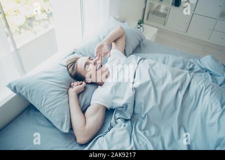 Oben über hohe Foto von positiven Fröhliche braunhaarige Mann wach aus gesunder Schlaf Gähnen zufrieden nach der Nacht träume im Zimmer Haus im Innenbereich Stockfoto