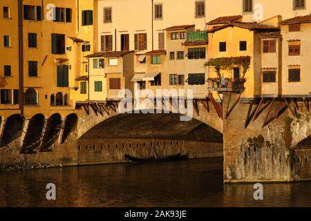 Italienische Gondel unter der Alten Brücke in Florenz (Italien) bei Sonnenaufgang. Stockfoto