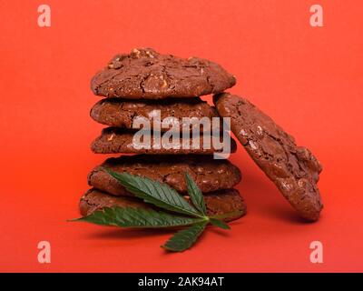 Glasierte Plätzchen mit Erdnüssen und Cannabis, Drogen Marihuana Cookies auf roten Hintergrund. Stockfoto