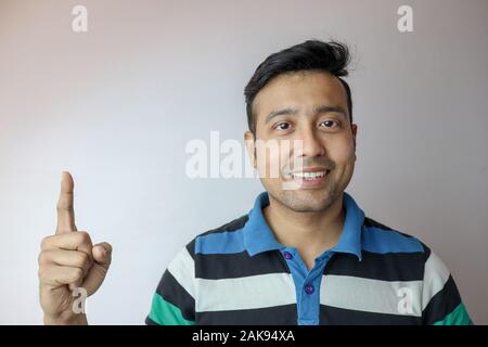 Ein junger Inder zuversichtlich und lächelnd an, dass ein Symbol auf weißem Hintergrund mit Kopie Platz für Text isoliert. Stockfoto