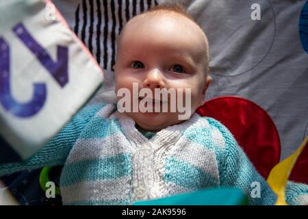 Eine glücklich lächelnde Junge Baby spielt auf einem sensorischen Entwicklung playmat Stockfoto