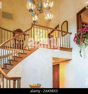 Quadratische Wendeltreppe im rustikalen Eintrag eines luxuriösen Kalifornien Haus mit warmer Beleuchtung Stockfoto