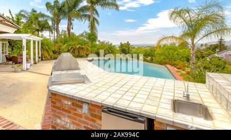 Panorama Tag geschossen von einem Wunder, Kalifornien Haus mit großem Pool und Platz für einen Grill an einem hellen, sonnigen Tag mit puffy Clouds Stockfoto