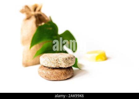 Solid shampoo Bremsscheiben schließen oben mit grünen Blättern und Jute Tasche, Beispiel für natürliche und ökologische Kunststoff frei Kosmetische, hausgemachte mit Kräutern Stockfoto