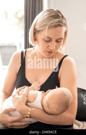 Junge Frau mit einem Baby auf ihre Hände und sah ihn an Stockfoto