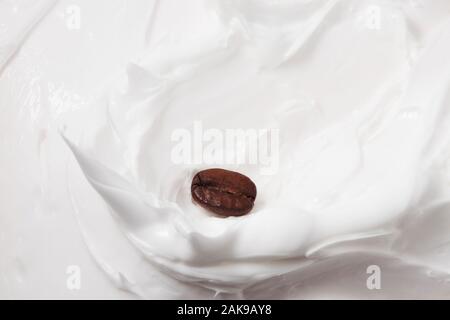 Kaffeemilchdessert. Kaffeebohnen zwischen Joghurt oder Milch. Nahaufnahme. Stockfoto