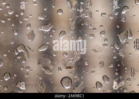 Regentropfen auf Fensterglas, verschwommenes gestreiften Hintergrund. Stockfoto