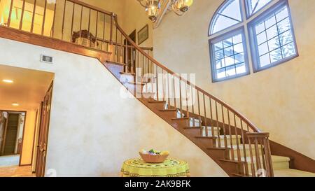 Panorama Spindeltreppe in einem warmen Landhausstil home mit Kronleuchter und einem kleinen Tisch Stockfoto