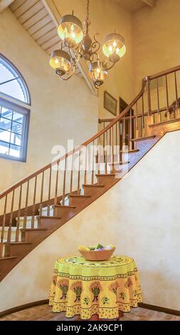 Vertikale rahmen Spindeltreppe in einem warmen Landhausstil home mit Kronleuchter und einem kleinen Tisch Stockfoto