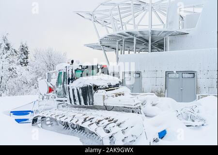 Schnee, den Traktor durch Schnee in weiss Winter Skigebiet abgedeckt. Stockfoto