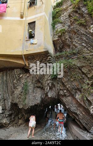 Sommertouristen, die den Höhlentunnel zum Strand im Fischerdorf Vernazza, Nationalpark Cinque Terre, Ligurien Italien EU nutzen Stockfoto