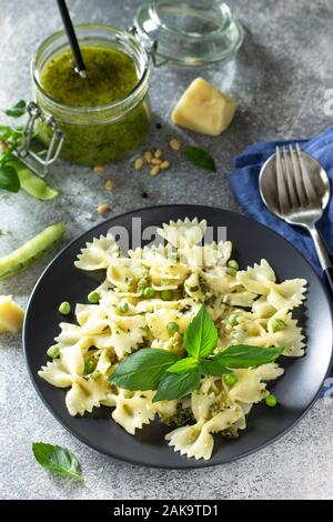 Gesunde italienische Küche. Pasta mit Erbsen und Pesto in schwarz Schüssel auf grauem Stein Hintergrund. Stockfoto