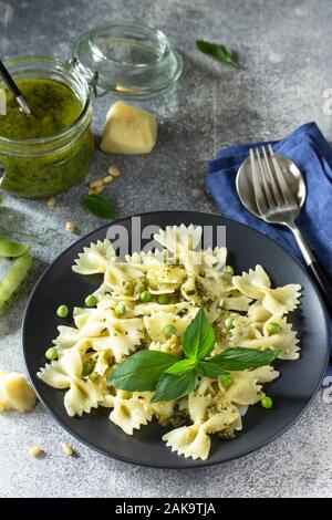 Gesunde italienische Küche. Pasta mit Erbsen und Pesto in schwarz Schüssel auf grauem Stein Hintergrund. Stockfoto