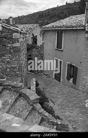 Backstreet (Rue du Porche) mit Treppen und Kopfsteinpflaster in der alten Katharer Dorf Minerve, Hérault, Royal, Frankreich. Schwarz und Weiss Stockfoto