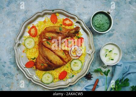 Huhn Kabsa/kuzhi Mandhi oder Mandi Biryani serviert mit Joghurt Minze Chutney Stockfoto