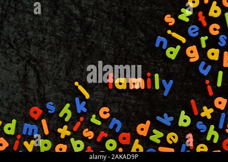 Das Wort Familie mit bunten magnetische Buchstaben auf schwarzem Grund Stockfoto