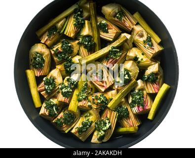 Kochen italienischen Artischocken in einer Pfanne mit einer Sauce aus Olivenöl, Zitronensaft und Petersilie. Gesundes Essen Stockfoto