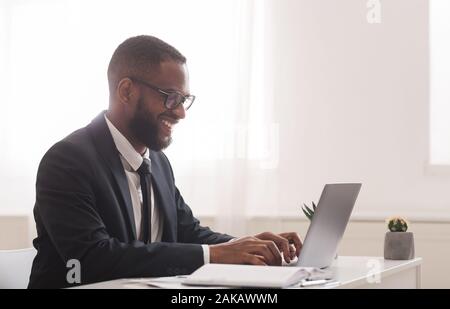 Afrikanische amerikanische Geschäftsmann arbeiten in modernen High-Tech-Büro, Schreibarbeiten auf Laptop, freier Speicherplatz, Seitenansicht Stockfoto