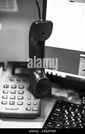 Schwarz-weiß Foto von den Hörer vor dem Hintergrund der Telefon- und Monitor mit geringer Tiefenschärfe Stockfoto