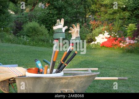 Schubkarre mit Gartengeräte in der Abendsonne nach der Arbeit, atmosphärische Konzept für heute genug glückliche Zeit im Garten Stockfoto