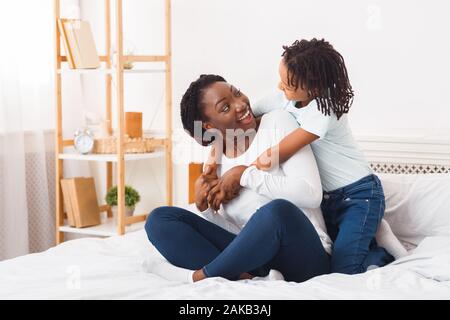 Familie im Schlafzimmer. Schwarze Mutter und Tochter Ausgabe Zeit zusammen im Bett in den Morgen. Freier Speicherplatz Stockfoto