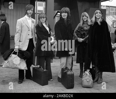 Beatles stars John Lennon (l) und George Harrison zusammen mit ihren Frauen, Cynthia Lennon (Zweite links) und Pattie Harrison (r), und Frau Harrison's Schwester Jenny Boyd am Flughafen Heathrow, London, vor dem Fliegen nach Indien. Stockfoto