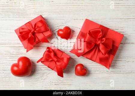Geschenkboxen mit Bogen und Herzen auf Holz- Hintergrund, Ansicht von oben Stockfoto