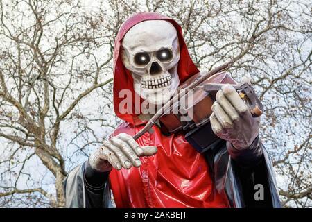 Grim Reaper, ein Skelett Abbildung Violine zu spielen, außerhalb haunted Attraction an Weihnachten Kirmes, Winter Wonderland, in London. Stockfoto