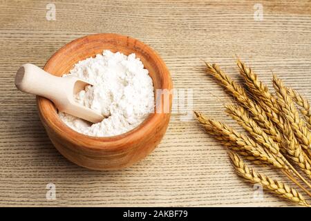 Mehl in einer Holzschüssel mit einer Holzlöffel auf einem Holztisch Stockfoto