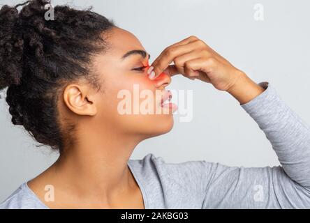 Empörte junge schwarze Frau berühren Nasensteg, rot markierten Zone, Seitenansicht Stockfoto