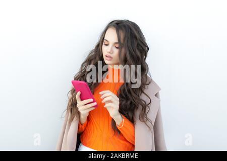 Mädchen sprechen, und auf einem Mobiltelefon Missverständnis und lächelt. emotionale Mädchen auf weißem Hintergrund. Stockfoto