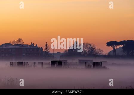 Schöne Aussicht eines Stadtteils in Nebel getaucht, im Licht des Sonnenuntergangs, Palaia, Toskana, Italien Stockfoto
