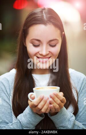 Hände Nahaufnahme von einer Frau mit einem heißen Kaffee Tasse außerhalb mit draußen im Hintergrund Stockfoto