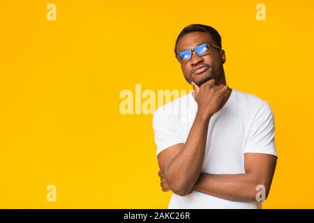 Dachte. Nachdenklich schwarze Kerl denken Berühren Kinn auf gelben Hintergrund. Studio Shot, Kopieren Raum Stockfoto