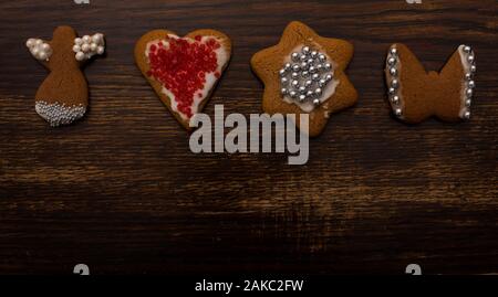 Hausgemachtes Lebkuchen in verschiedenen Formen mit weißer Vereisung und buntem Zuckerdekor auf dem Hintergrund eines alten Holztisches Stockfoto