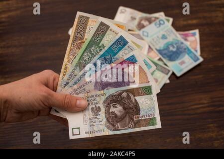 Aus verschiedenen Banknoten polnischen Geld, Zloty schließen, PLN, die sich in einem Ventilator Form in den Händen auf einem alten Holz- Hintergrund Stockfoto