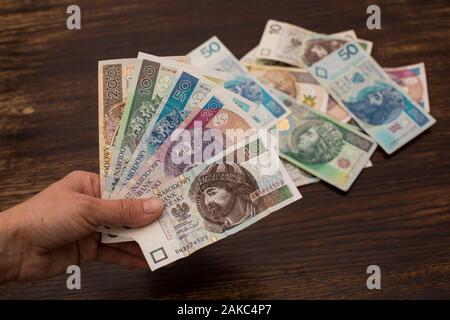 Aus verschiedenen Banknoten polnischen Geld, Zloty schließen, PLN, die sich in einem Ventilator Form in den Händen auf einem alten Holz- Hintergrund Stockfoto