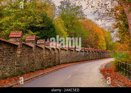 Alte Steinmauer der Abtei von Clervaux, Kloster Saint-Maurice und Saint-Maur Benediktiner in Luxemburg und auf der Straße durch den Wald im Herbst Stockfoto