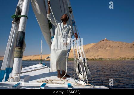 Ägypten, Oberägypten, Assuan, Nubischen sailor Vor seiner Feluke alle Segel errichtet, Segeln auf dem Nil vor einer hohen Düne der linken Bank Stockfoto