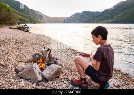 Serbien, Golubac, Clement kümmert sich um das Feuer für das Abendessen am Ufer der Donau Stockfoto