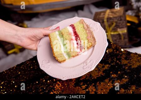 Golden leuchtenden lecker Kuchen wird in Stücke geschnitten. Ein Stück Kuchen auf einem rosa Platte. Hausgemachte Backen für Kinder Party. Stockfoto