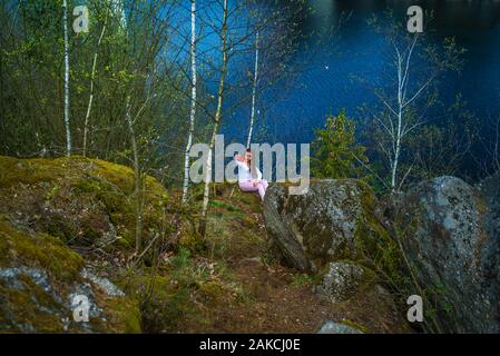 Ein Mädchen schaut aus einer Höhe am Fluss. ein Mädchen in einem Park in der Nähe ein Erholungsgebiet in der Natur sitzt. Ein junges Mädchen steht in der Nähe einer Klippe, und schaut nach unten. Stockfoto